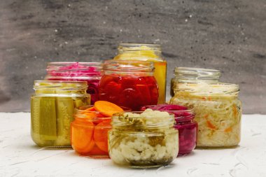 Cam kavanozlarda mayalanmış sebzeler. Mevsimlik sebze konsepti, sağlıklı yaşam tarzı için probiyotik gıdası. Beyaz macun arkaplanı, kopyalama alanı