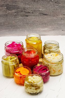 Cam kavanozlarda mayalanmış sebzeler. Mevsimlik sebze konsepti, sağlıklı yaşam tarzı için probiyotik gıdası. Beyaz macun arkaplanı, kopyalama alanı