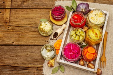 Cam kavanozlarda mayalanmış sebzeler. Mevsimlik sebze konsepti, sağlıklı yaşam tarzı için probiyotik gıdası. Kaliteli ahşap masa, üst manzara