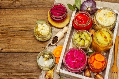 Cam kavanozlarda mayalanmış sebzeler. Mevsimlik sebze konsepti, sağlıklı yaşam tarzı için probiyotik gıdası. Kaliteli ahşap masa, üst manzara