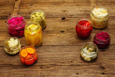 Cam kavanozlarda mayalanmış sebzeler. Mevsimlik sebze konsepti, sağlıklı yaşam tarzı için probiyotik gıdası. Eski tahta tablo, kopyala alanı