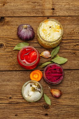 Cam kavanozlarda mayalanmış sebzeler. Mevsimlik sebze konsepti, sağlıklı yaşam tarzı için probiyotik gıdası. Kaliteli ahşap masa, üst manzara