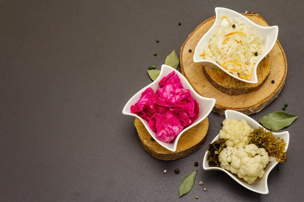 Farklı türde lahana turşusu. Mayalanmış yiyecekler sağlığınız için harikadır. Probiyotik beslenme konsepti, seramik kaseler ve ahşap tezgah, üst manzara.