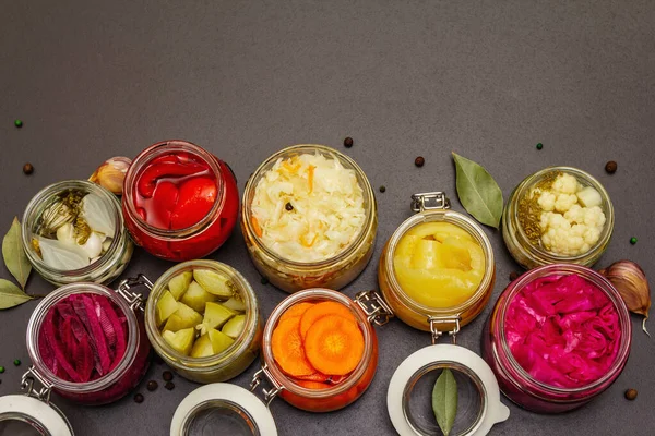 Cam kavanozlarda mayalanmış sebzeler. Mevsimlik sebze konsepti, sağlıklı yaşam tarzı için probiyotik gıdası. Siyah taş arkaplan, üst görünüm