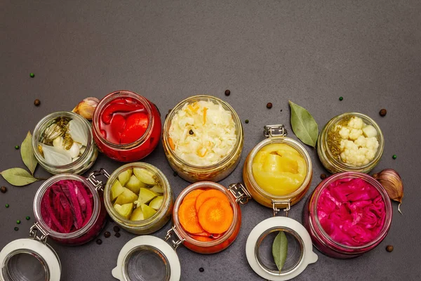 Cam kavanozlarda mayalanmış sebzeler. Mevsimlik sebze konsepti, sağlıklı yaşam tarzı için probiyotik gıdası. Siyah taş arkaplan, üst görünüm