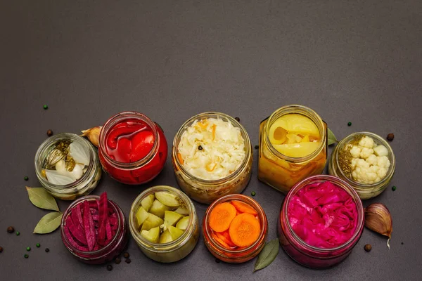 Cam kavanozlarda mayalanmış sebzeler. Mevsimlik sebze konsepti, sağlıklı yaşam tarzı için probiyotik gıdası. Siyah taş arkaplan, üst görünüm