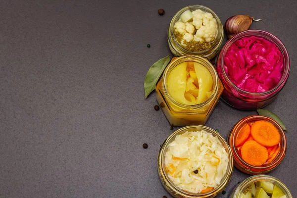 Cam kavanozlarda mayalanmış sebzeler. Mevsimlik sebze konsepti, sağlıklı yaşam tarzı için probiyotik gıdası. Siyah taş arkaplan, üst görünüm