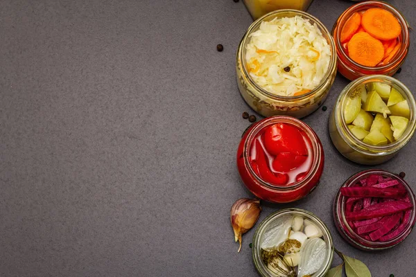 Cam kavanozlarda mayalanmış sebzeler. Mevsimlik sebze konsepti, sağlıklı yaşam tarzı için probiyotik gıdası. Siyah taş arkaplan, üst görünüm