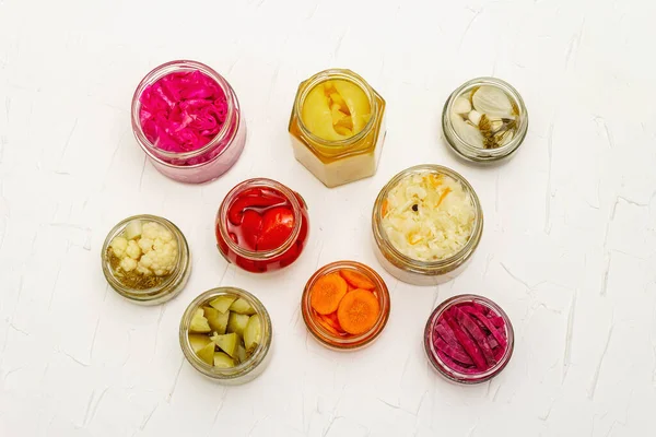 Cam kavanozlarda mayalanmış sebzeler. Mevsimlik sebze konsepti, sağlıklı yaşam tarzı için probiyotik gıdası. Beyaz macun arkaplan, üst görünüm