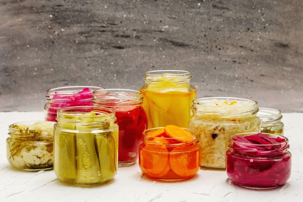 Cam kavanozlarda mayalanmış sebzeler. Mevsimlik sebze konsepti, sağlıklı yaşam tarzı için probiyotik gıdası. Beyaz macun arkaplanı, kopyalama alanı