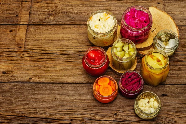 Cam kavanozlarda mayalanmış sebzeler. Mevsimlik sebze konsepti, sağlıklı yaşam tarzı için probiyotik gıdası. Kaliteli ahşap masa, üst manzara