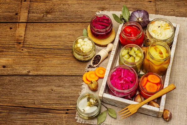 Cam kavanozlarda mayalanmış sebzeler. Mevsimlik sebze konsepti, sağlıklı yaşam tarzı için probiyotik gıdası. Kaliteli ahşap masa, üst manzara