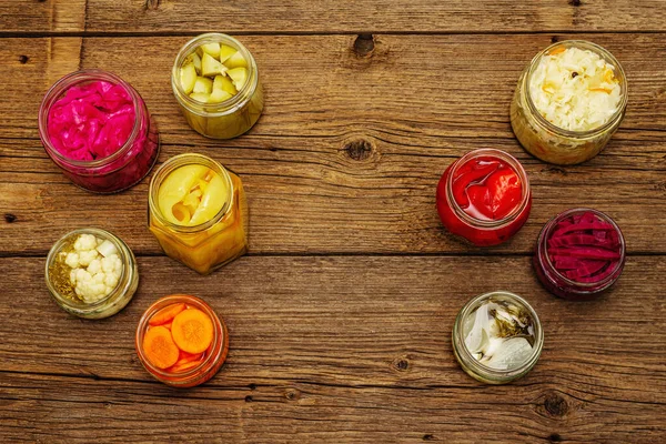 Cam kavanozlarda mayalanmış sebzeler. Mevsimlik sebze konsepti, sağlıklı yaşam tarzı için probiyotik gıdası. Kaliteli ahşap masa, üst manzara