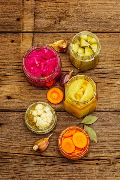 Cam kavanozlarda mayalanmış sebzeler. Mevsimlik sebze konsepti, sağlıklı yaşam tarzı için probiyotik gıdası. Kaliteli ahşap masa, üst manzara