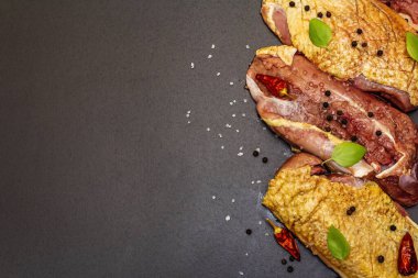 Çiğ ördek göğsü, deniz tuzu, taze fesleğen, acı biber ve baharat. Kümes hayvanları, doğal BIO ürünü, evcil kümes hayvanı. Siyah taş arkaplan, üst görünüm