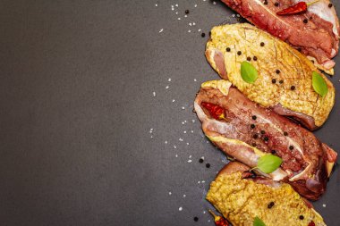 Çiğ ördek göğsü, deniz tuzu, taze fesleğen, acı biber ve baharat. Kümes hayvanları, doğal BIO ürünü, evcil kümes hayvanı. Siyah taş arkaplan, üst görünüm