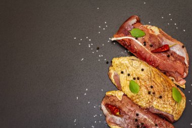 Çiğ ördek göğsü, deniz tuzu, taze fesleğen, acı biber ve baharat. Kümes hayvanları, doğal BIO ürünü, evcil kümes hayvanı. Siyah taş arkaplan, üst görünüm