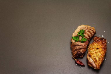 Taze maydanozlu, acılı ve karabiberli kızarmış ördek göğsü, deniz tuzu. Lezzetli yiyecekler, siyah taş üzerinde dilimlenmiş et beton arka plan, kopyalama alanı