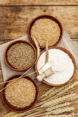 Ekmek pişirmek için gereken malzemeler: buğday kulakları ve bir kase un ve tahıl. Kaliteli ahşap masa, hamur yoğurma, üst manzara.