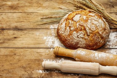 Buğday kulaklı ve okkalı taze ekmek. Eski ahşap tahta masa, hamur yoğurma, kopyalama alanı