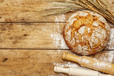 Buğday kulaklı ve okkalı taze ekmek. Kaliteli ahşap masa, hamur yoğurma, üst manzara.