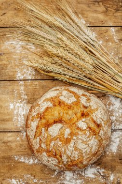 Buğday kulaklı taze ekmek. Kaliteli ahşap masa, hamur yoğurma, üst manzara.