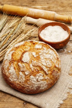 Buğday kulaklı taze ekmek, bir kase un ve oklavalarla. Kaliteli ahşap tahta masa, hamur yoğurma, kapat