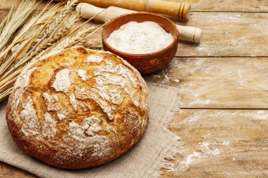 Buğday kulaklı taze ekmek, bir kase un ve oklavalarla. Eski ahşap tahta masa, hamur yoğurma, kopyalama alanı