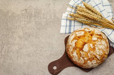 Buğday kulaklı taze ekmek ve kaliteli keten peçete. Gri taş arkaplan, üst manzara