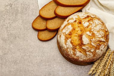 Buğday kulaklı taze ekmek ve kaliteli keten peçete. Gri taş arkaplan, üst manzara