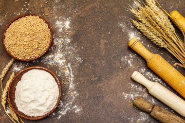 Ekmek pişirmek için gereken malzemeler: buğday kulakları ve bir kase un ve tahıl. Taş beton arka plan, hamur yoğurma, üst manzara