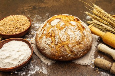 Buğday kulaklı taze ekmek, bir kase un ve tahıl. Kaliteli ahşap tahta masa, hamur yoğurma, kapat