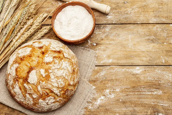 Buğday kulaklı taze ekmek, bir kase un ve oklavalarla. Kaliteli ahşap masa, hamur yoğurma, üst manzara.