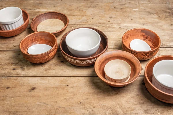 Handmade empty ceramic dishes and plates on wooden background. Collections of various bowls, traditional folk ornament, rustic style, vintage table. Passover table concept, copy space