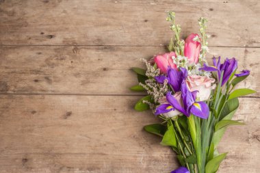 Eski ahşap tahtaların üzerinde güzel bir buket düğün çiçeği. 8 Mart ya da Sevgililer Günü için bayram hediyesi konsepti. Tebrik kartı, metin için bir yer, üst görünüm