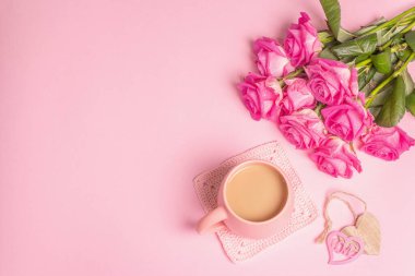 Güzel bir buket gülle sabah kahvesi. Romantik kahvaltı konsepti, ahşap kalpler, şenlik havası. Pastel pembe arkaplan