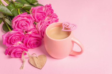 Güzel bir buket gülle sabah kahvesi. Romantik kahvaltı konsepti, ahşap kalpler, şenlik havası. Pastel pembe arkaplan