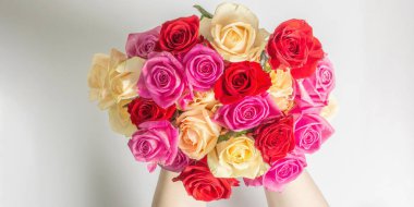 Kadının elleri çok güzel bir buket taze renkli gül tutuyor. Beyaz arkaplanda izole edilmiş çiçek bileşimi. Kutlama kartı konsepti