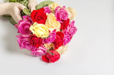 Kadının elleri çok güzel bir buket taze renkli gül tutuyor. Beyaz arkaplanda izole edilmiş çiçek bileşimi. Kutlama kartı konsepti
