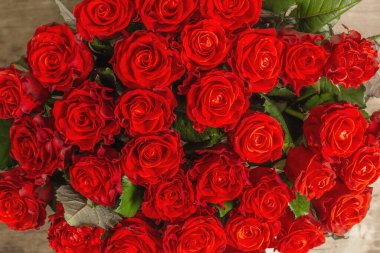 Taze kırmızı güllerden oluşan gür bir buket. Klasik ahşap arka planda çiçek kompozisyonu. Kutlama kartı konsepti, üst görünüm