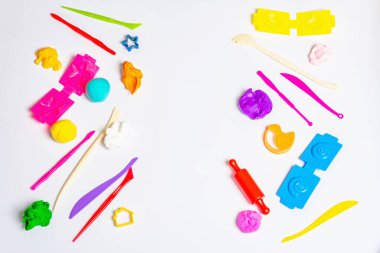 Beyaz zemin üzerinde renkli modelleme kil, araçlar ve formlar izole. Kil ile eğitici bir oyun. Çocuklar kilden figürler yontuyorlar. Erken kalkınma kavramı, üst görünüm