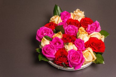 Seramik standında çok renkli taze güllerin kompozisyonu. Düğünler, doğum günleri, 8 Mart, anneler günü ya da sevgililer günü için festival konsepti. Tebrik kartı, düz yatış, siyah taş zemin