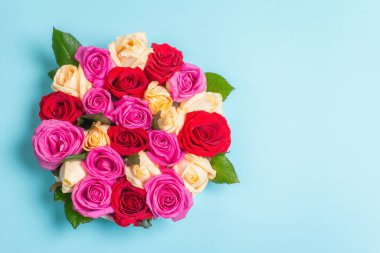 Seramik standında çok renkli taze güllerin kompozisyonu. Düğünler, doğum günleri, 8 Mart, anneler günü ya da sevgililer günü için festival konsepti. Tebrik kartı, düz yatış, mat mavi arkaplan