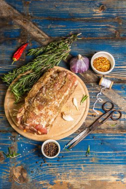 Sarımsak ve havuçla doldurulmuş çiğ domuz eti. Kızartma, baharat, biberiye, mutfak ipi ve klasik makas için taze et hazır. Eski ahşap masa, üst manzara.