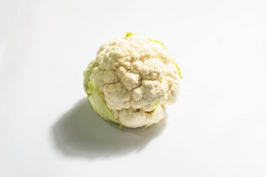 Beyaz arka planda izole edilmiş taze bir karnabahar başı. Çiğ sebze, sağlıklı gıda konsepti, vejetaryen ya da vejetaryen yaşam tarzı. Modaya uygun sert ışık, koyu gölge, düz uzanma, model, şablon