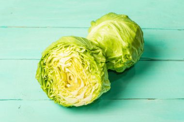 Taze lahana, yarısı ve tamamı moda turkuaz ahşap arka planda. Bahar salatası kesmek için sebzeler. Vejetaryen yemeği, diyet, vitamin