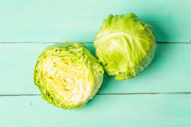 Taze lahana, yarısı ve tamamı moda turkuaz ahşap arka planda. Bahar salatası kesmek için sebzeler. Vejetaryen yemeği, diyet, vitamin