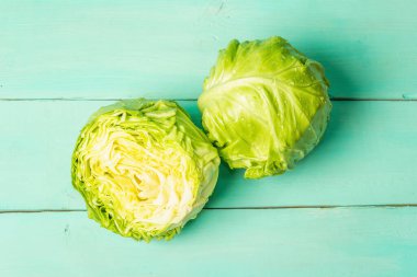 Taze lahana, yarısı ve tamamı moda turkuaz ahşap arka planda. Bahar salatası kesmek için sebzeler. Vejetaryen yemeği, diyet, vitamin