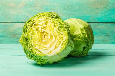 Taze lahana, yarısı ve tamamı moda turkuaz ahşap arka planda. Bahar salatası kesmek için sebzeler. Vejetaryen yemeği, diyet, vitamin