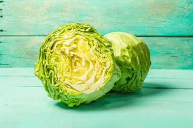 Taze lahana, yarısı ve tamamı moda turkuaz ahşap arka planda. Bahar salatası kesmek için sebzeler. Vejetaryen yemeği, diyet, vitamin